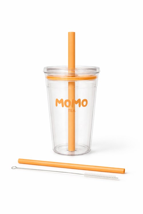 Clear tumbler with orange straw and cleaning brush on a white background